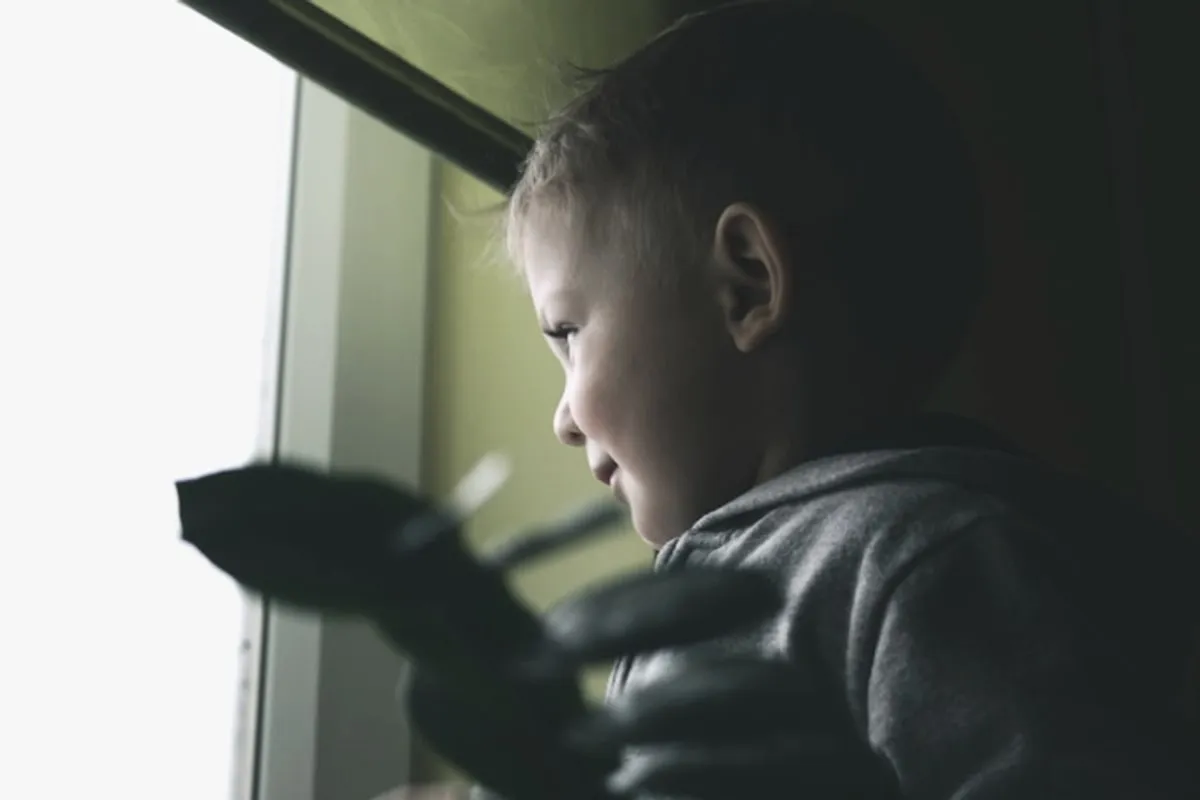 A child looking out of a tall window in the waiting room.